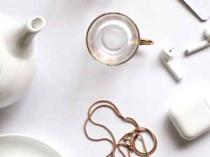 Minimalist flat lay featuring gold jewelry, glass cups, and a white tea set, perfect for luxury lifestyle themes.